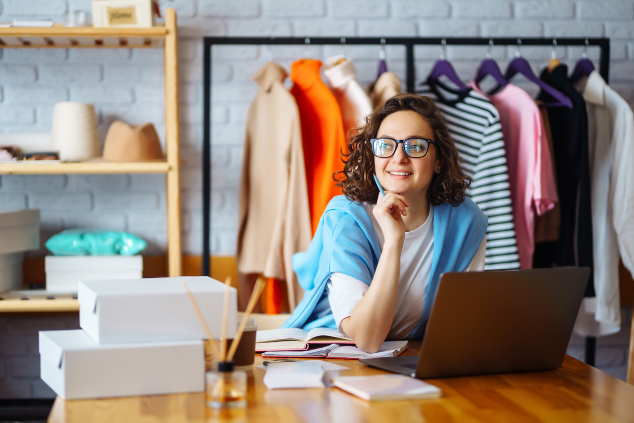 Smiling small business owner taking notes on orders on a laptop